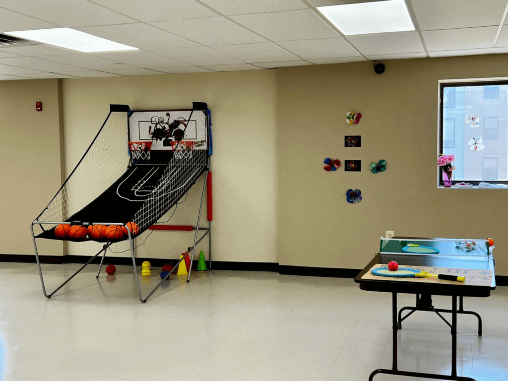 Arcade basketball hoop and a ping pong table in the games area at Penn Village
