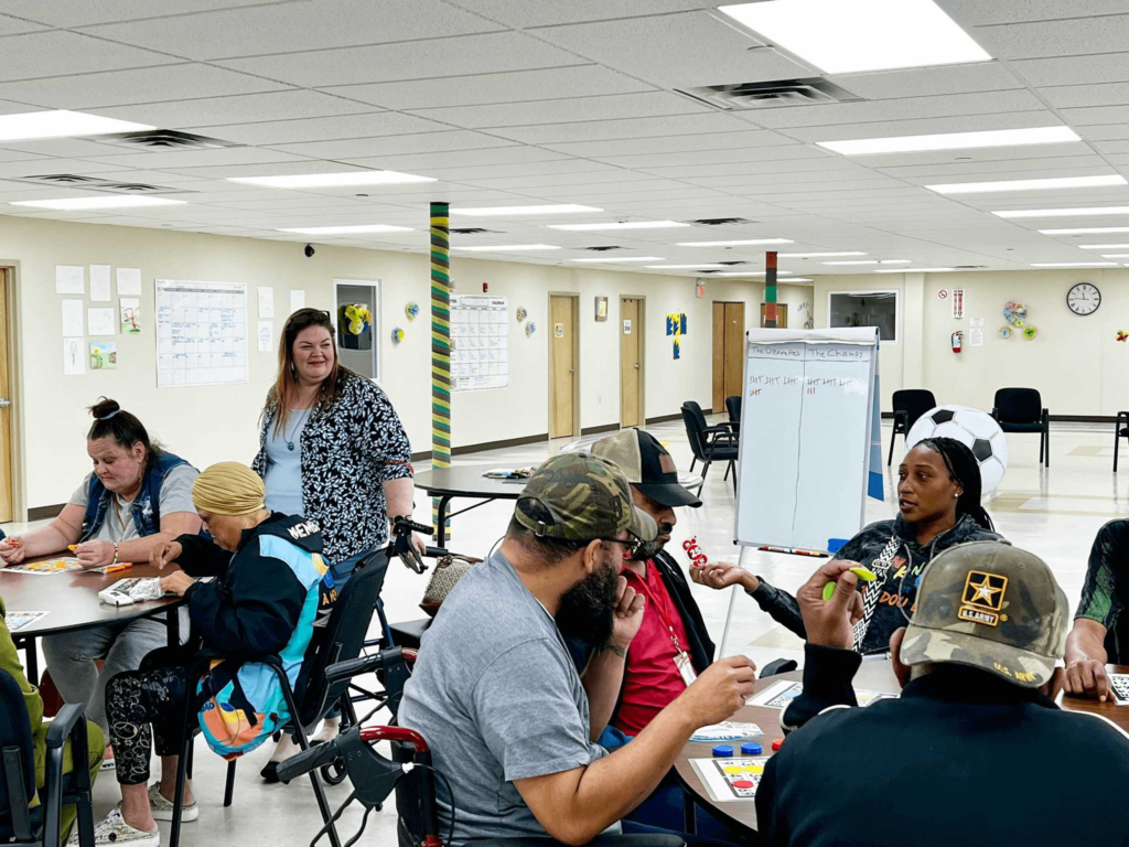 A staff member helping members with an afternoon activity at a table at Penn Village Adult Day Care
